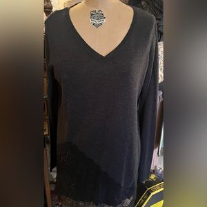 Women’s black V-neck, long sleeved sweater with lace trim at the bottom.